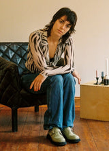 Load image into Gallery viewer, Frau in Bluse mit Zebramuster und Jeans sitzt in einem Ledersessel. Sie trägt hellgrüne Monk-Schuhe aus Leder von Cedoublé.