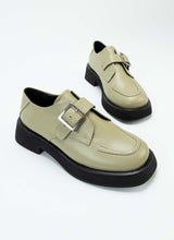 Load image into Gallery viewer, Ein Paar Halbschuhe aus zertifiziertem Glattleder. Dieses Modell eignet sich für alle Geschlechter und hält sich nicht an Trends. Es handelt sich um einen sogenannten Monk mit einer Schnalle. Die besondere Farbe, ein Pastellgrün, die dezente Sohle mit Plateau und die Ziernaht auf der Front unterstreichen den nicht alltäglichen Charakter dieses Schuhs.