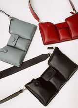 Lade das Bild in den Galerie-Viewer, Three leather bags on a white background. Two are made out of puffy leather – one in dark red and one in black – and the third one is made out of grey, pebbled leather.
