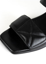 Load image into Gallery viewer, Detailfoto einer minimalistischen Sandale in schwarzem Glattleder mit Karree Leisten und zwei gepolsterten Riemen mit dekorativen Nähten im Quilted-Look

