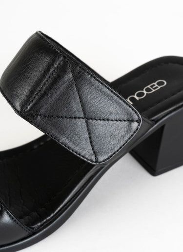 Detailfoto einer eleganten, aber alltagstauglichen Sandale in schwarzem Glattleder mit dekorativen Nähten an den Enden zweier gepolsterter Riemen.