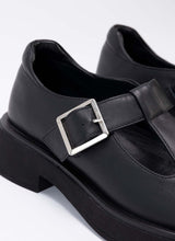 Load image into Gallery viewer, Detailaufnahme eines schwarzen Mary Jane Schuhs mit einer Laufsohle mit leichtem Plateau. Abgerundet wird der Schulmädchen-Look durch eine silberfarbene Schnalle. Obermaterial und Futter sind aus weichem, schwarzem Echtleder.
