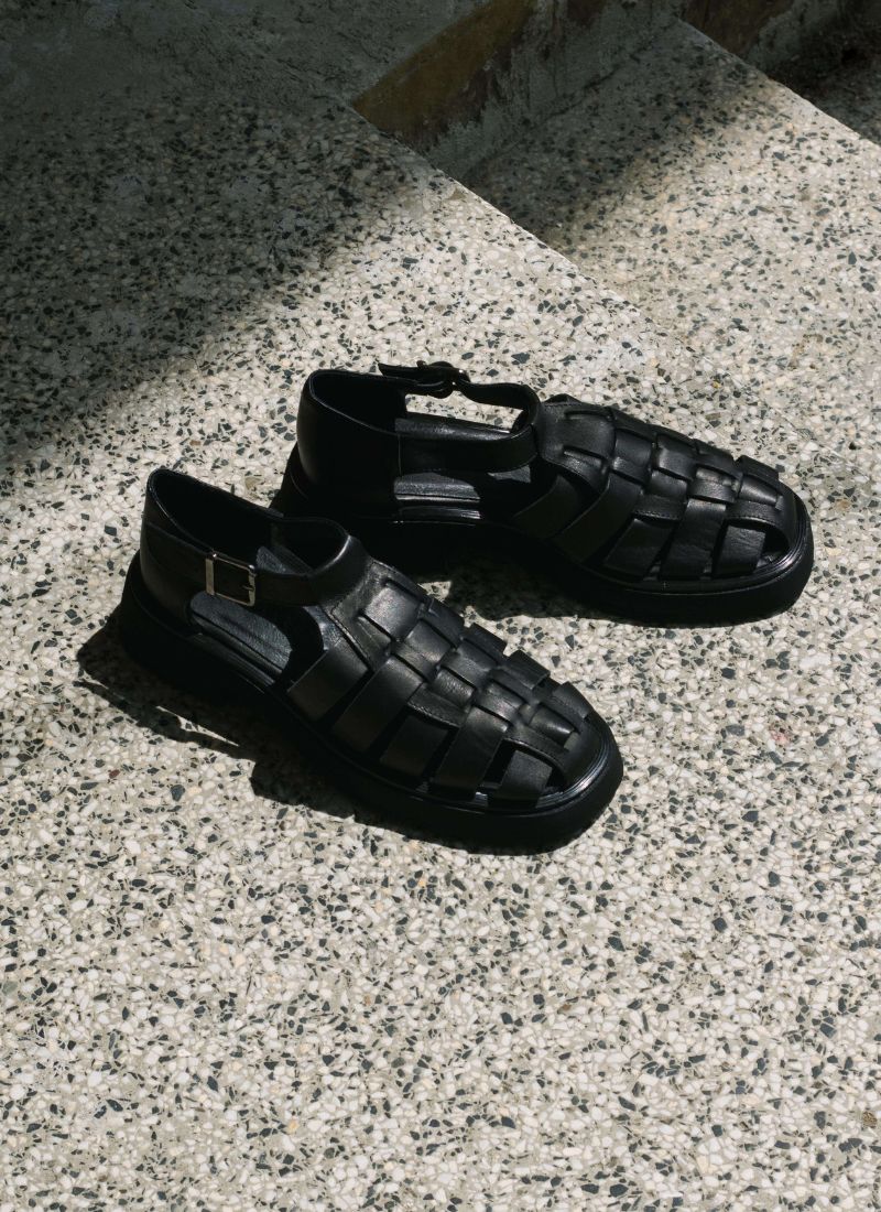 Black leather unisex fisherman sandals with chunky outsole illuminated by the sun