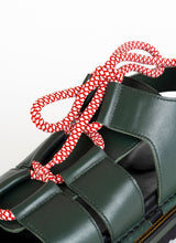 Load image into Gallery viewer, Detailfoto einer geschnürten Bäcker-Sandale aus dunkelgrünem Glattleder mir rot-weißen Rundsenkeln von CEDOUBLÉ.
