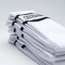 Aufeinander gestapelte Tennissocken des Labels Cedoublé in weiß-schwarz mit Logo. Es handelt sich um ein Produktbild. Auf dem Foto gut ersichtlich ist die Qualität aus Bio-Baumwolle. Die Strümpfe sind unisex tragbar.