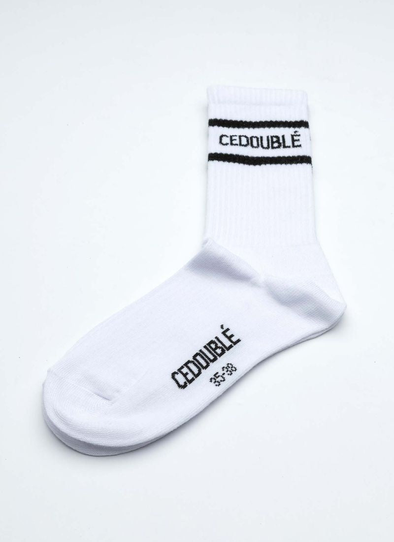 Produktfoto einer Tennissocke aus organic cotton in weiß mit schwarzen Details wie dem Logo des Herstellers Cedoublé. Tragbar für alle Geschlechter. Die Socke hat eine mittlere Länge.