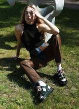 Load image into Gallery viewer, Model auf einer Wiese mit Lederhose und Top bekleidet. An den Füßen trägt sie Socken und chunky Leder Sandalen von Cedoublé.
