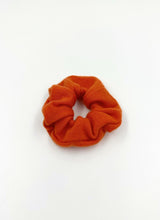 Load image into Gallery viewer, Butterweiches Scrunchie aus reinem, orangefarbenem Kaschmir. Die Oberfläche ist zart und flauschig.
