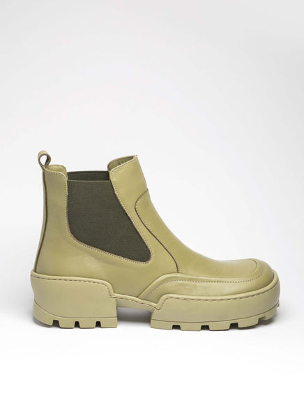 Seitliche Ansicht eines ledernen Lug Boots in chunky Karreeform. Diese Boots sind von dem non-seasonal Label Cedoublé und überzeugen mit einer dicken und dennoch flexiblen Laufsohle aus Gummi. Der elastische Elastikeinsatz ist typisch für ein Chelsea-Modell und passt farblich perfekt zu der grünen Lederfarbe. Die Lug Boots erinnern an Styles von Bottega Veneta und Ganni, wirken aber noch jünger, frischer und überraschend anders.