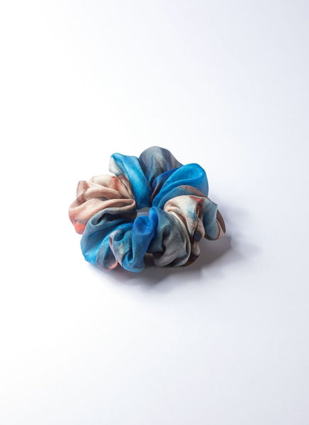 Scrunchie aus reiner, gebatikter Seide mit Farbverläufen von Naturtönen und Blau. Es handelt sich um einen zarten, leichten Seidenstoff. Das Volumen ist bauschig.