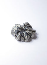 Load image into Gallery viewer, Silber-graues Scrunchie aus 100% upcycled Seide. Das Haargummi wurde aus einem Seidentuch recycelt und ist nachhaltig. Lokale Herstellung in Deutschland. 
